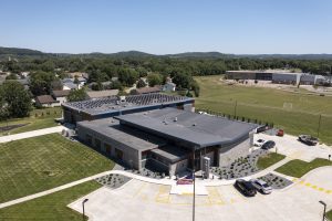 Aerial photograph of an expansive new police station in Sauk City Wisconsin with V-shaped roof, solar array and beautiful landscaping.