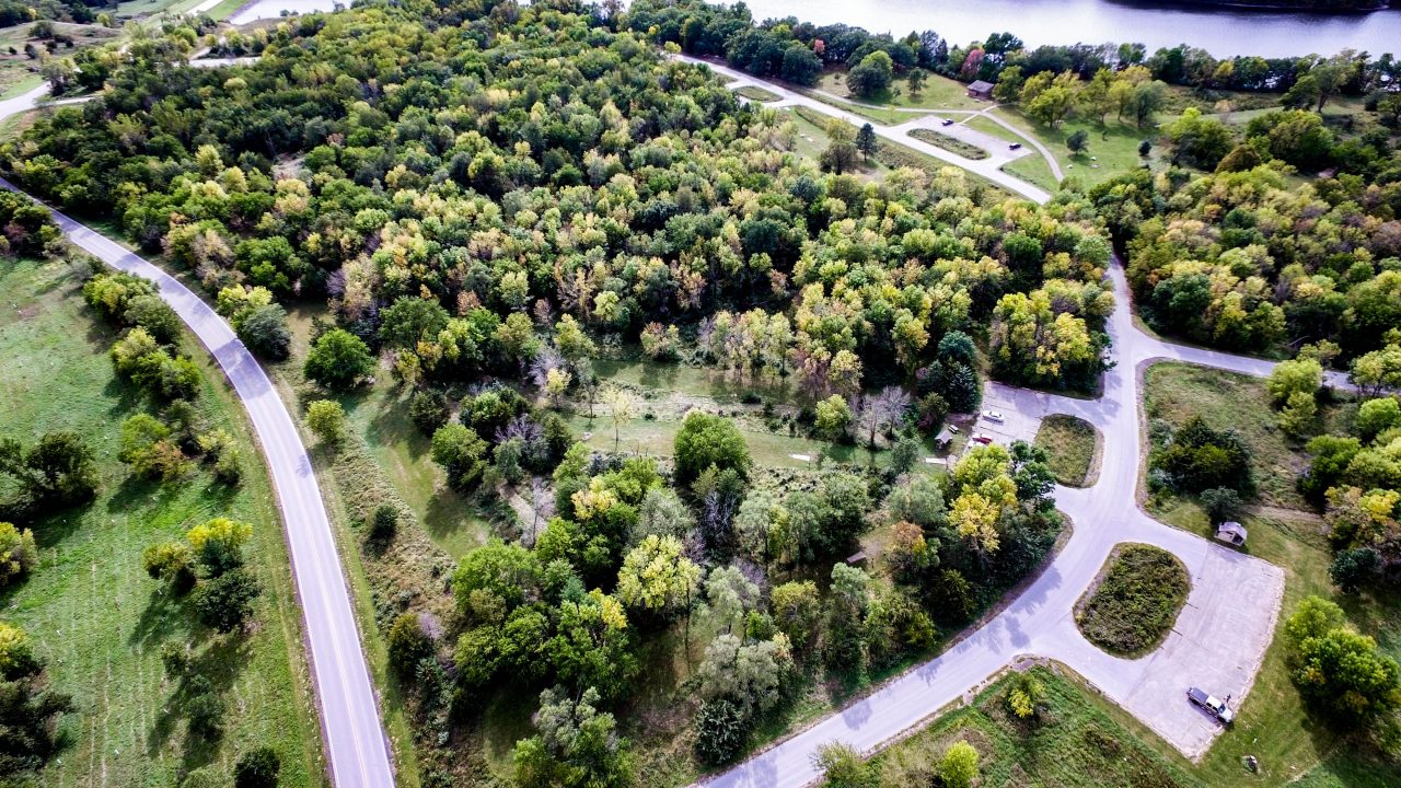 Aerial photograph of Iowa state park, with visitor parking lots, trees, and a river flowing through.