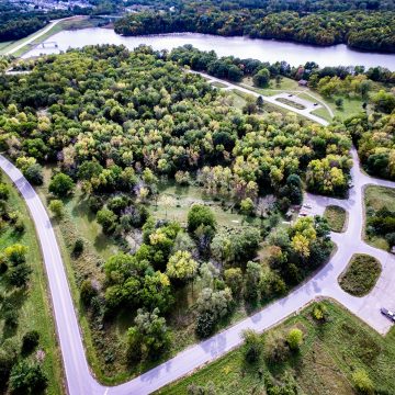 Aerial photograph of Iowa state park, with visitor parking lots, trees, and a river flowing through.