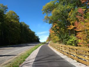 Image of paved bike and pedestrian trail with wooden fence and autumn leaves as part of the newly complete Conover-Phelps trail in Phelps, Wisconsin. 