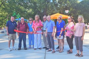 A group of people posing with ceremonial ribbon and scissors to mark the grand opening of a new community splash pad at Swan Park in Beaver Dam, Wisconsin.