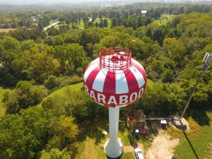 Aerial photograph of red and white striped water tower in Baraboo, Wisconsin, that resembles a circus tent and pays homage to the cultural roots of the community as home to the Ringling Brothers and Circus World Museum.